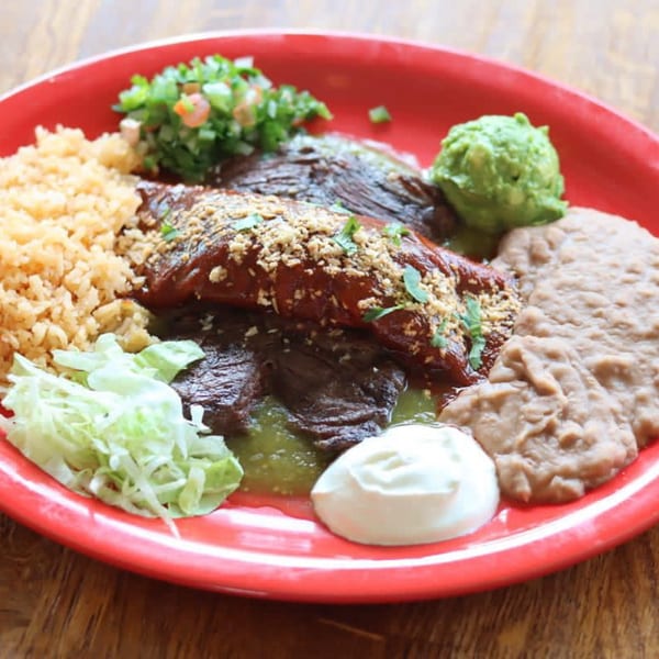 A La Mex Mexican combo plate with enchiladas, rice, beans, guacamole, pico de gallo, and sour cream.