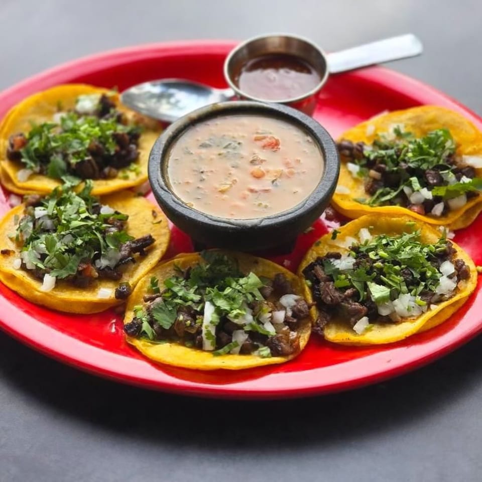 Five La Mex street tacos with meat, onions, and cilantro, served with two dipping sauces.
